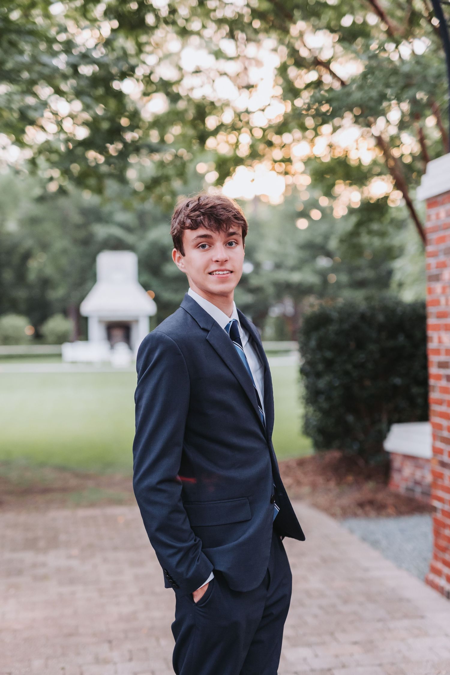 A candid outdoor portrait with soft evening light filtering through trees in a garden setting.