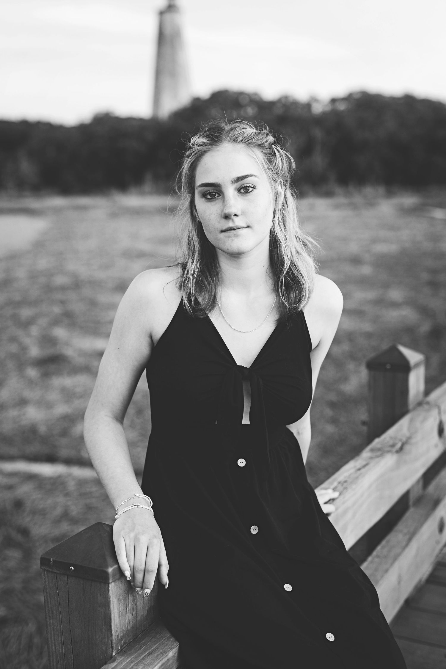 Black and white portrait on wooden dock with lighthouse in background.