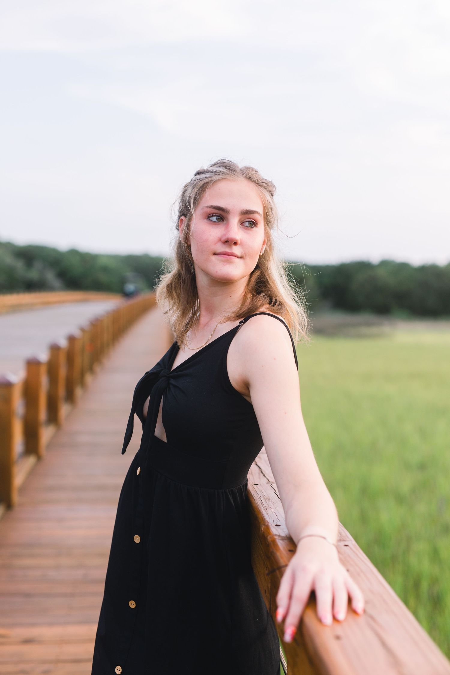 Summer fashion photo on wooden boardwalk with coastal scenery in background.
