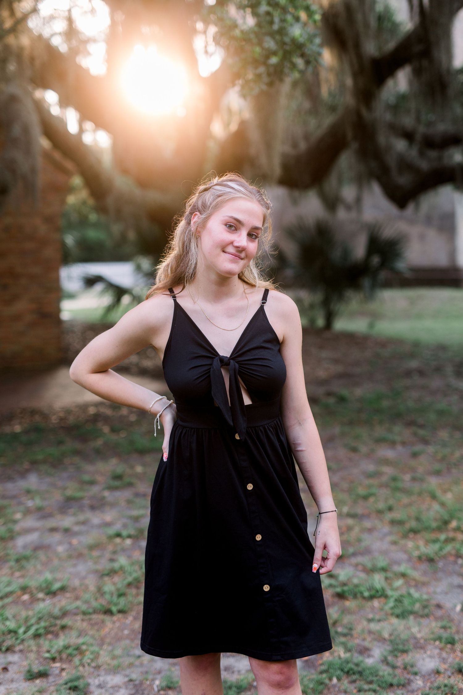 Black sundress against sunset through Spanish moss trees in coastal setting.
