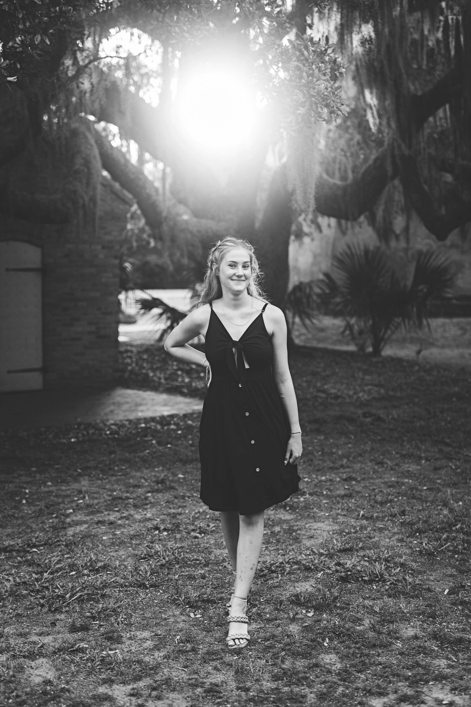 Black and white portrait with sunburst through trees in Southern garden setting.