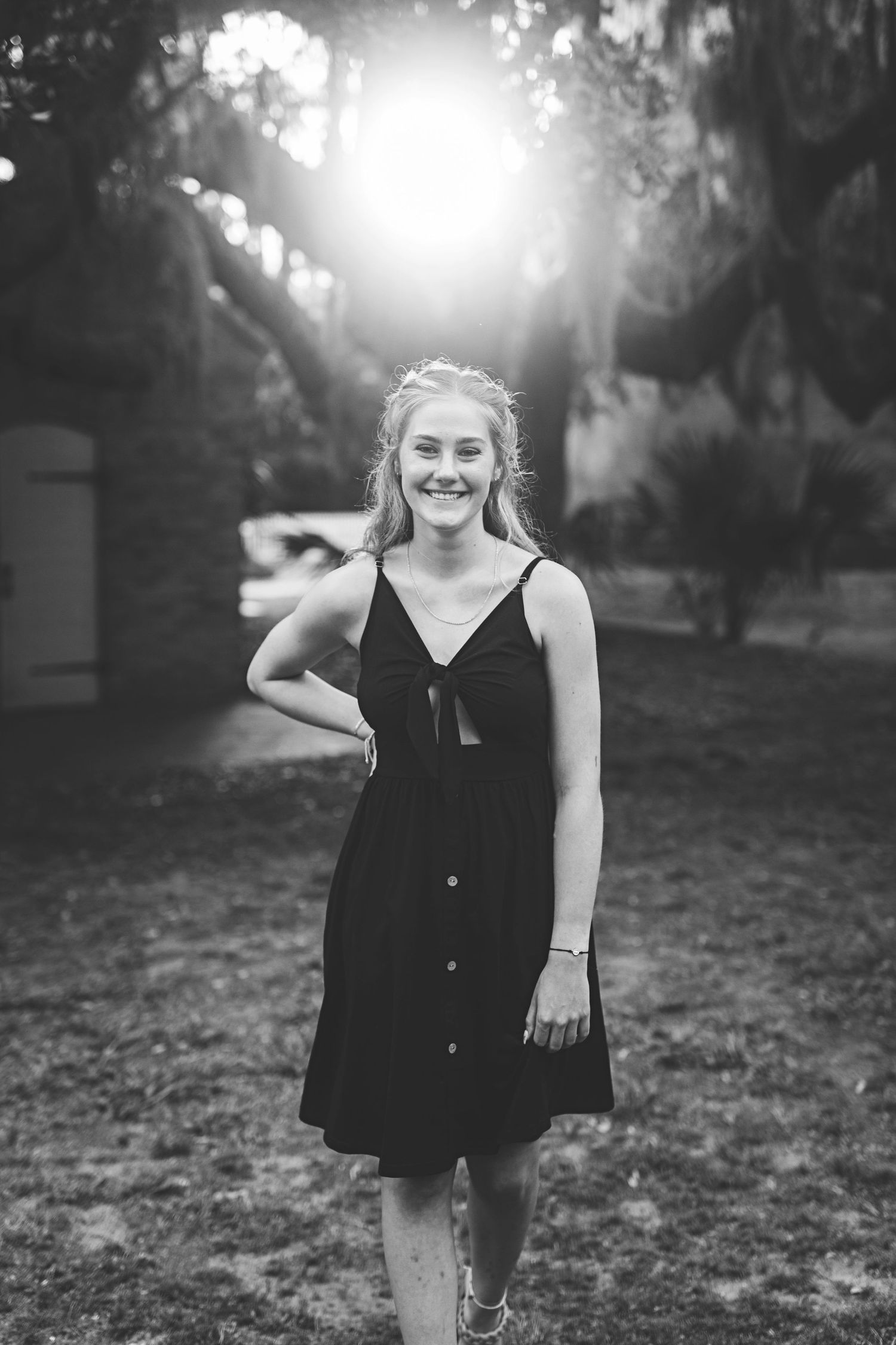 Black and white summer portrait with dramatic backlighting through trees.