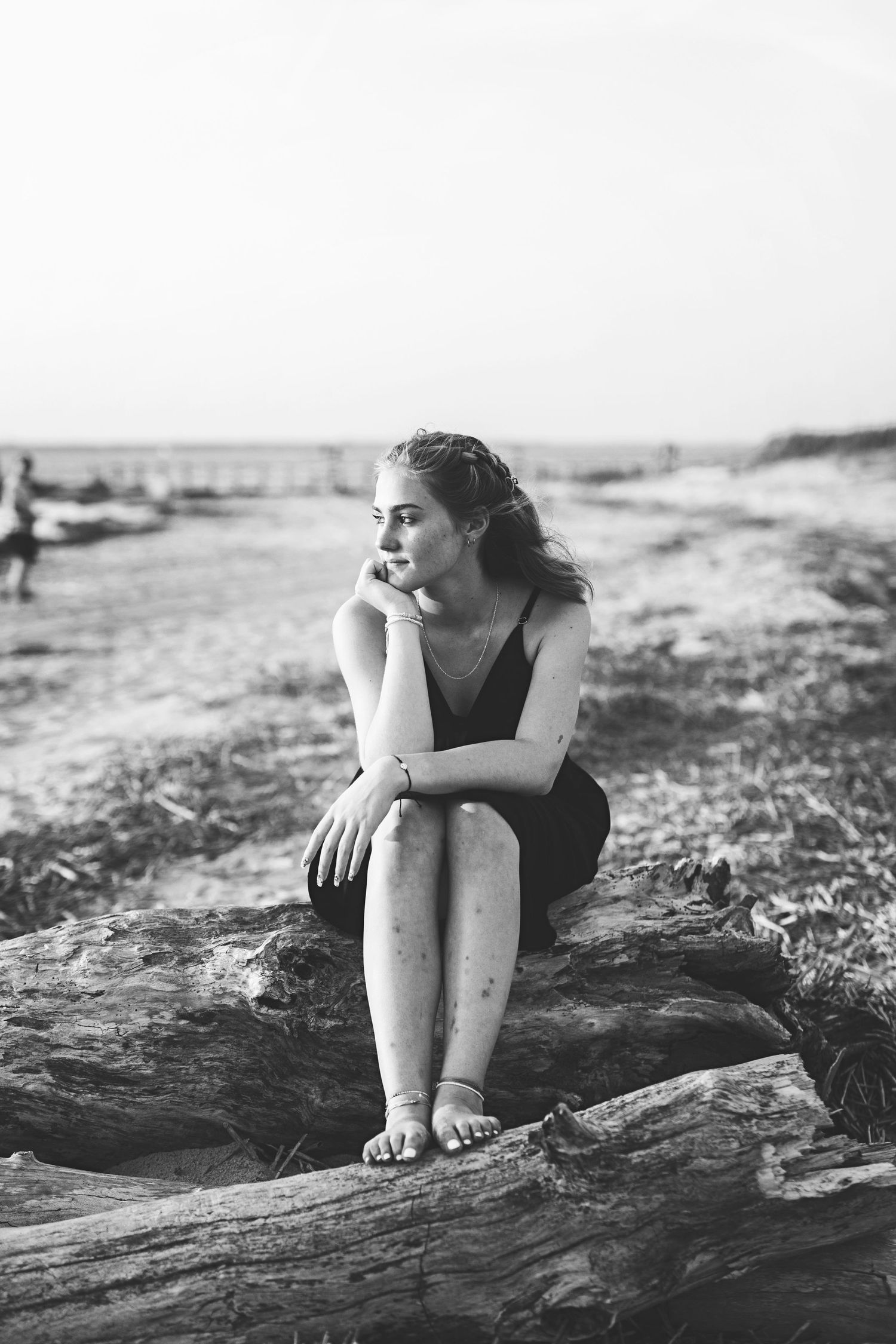 Black and white coastal portrait on driftwood with moody seaside atmosphere.
