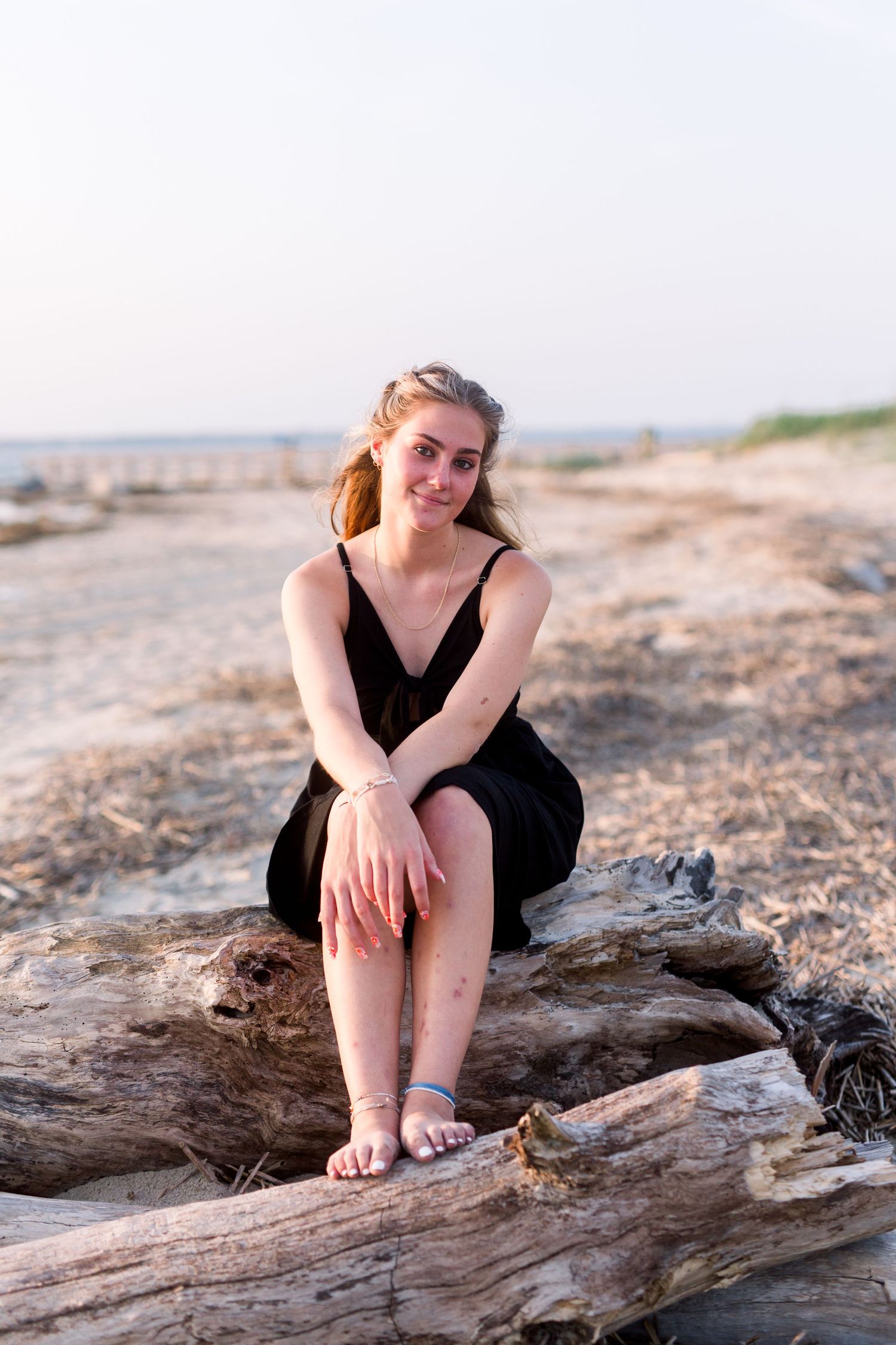 Summer portrait on driftwood at beach during golden hour.