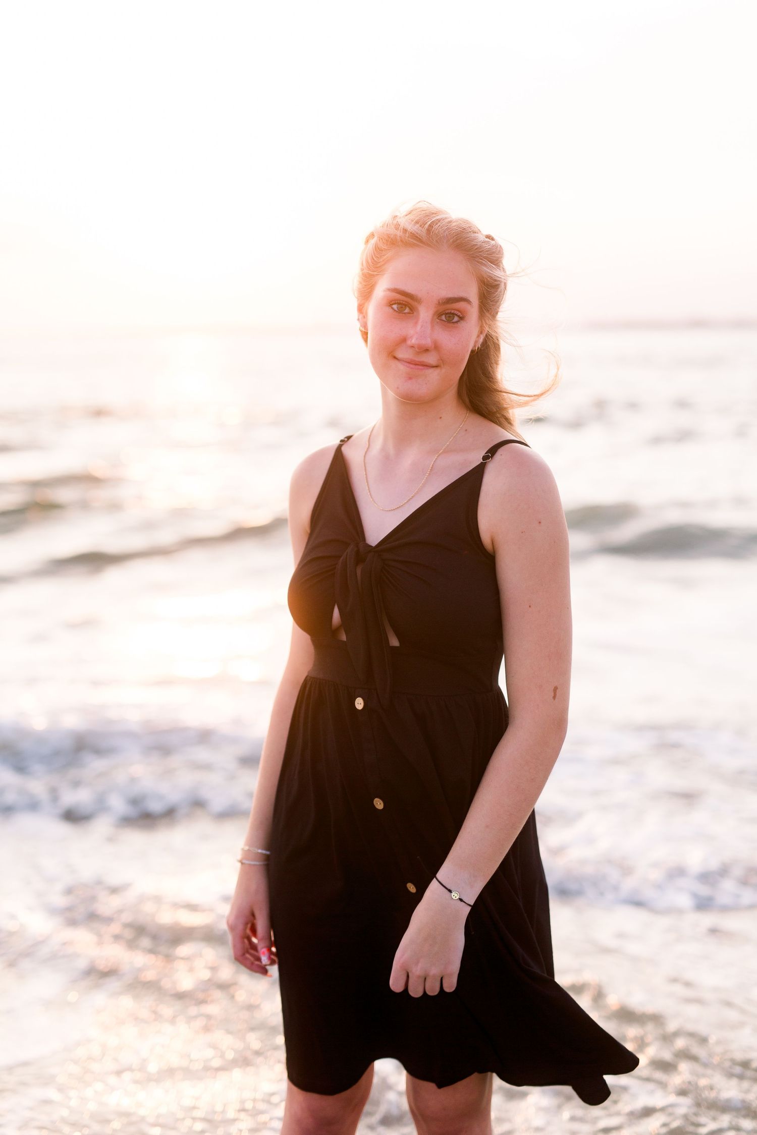 Black sundress flows in ocean breeze during golden hour photoshoot.