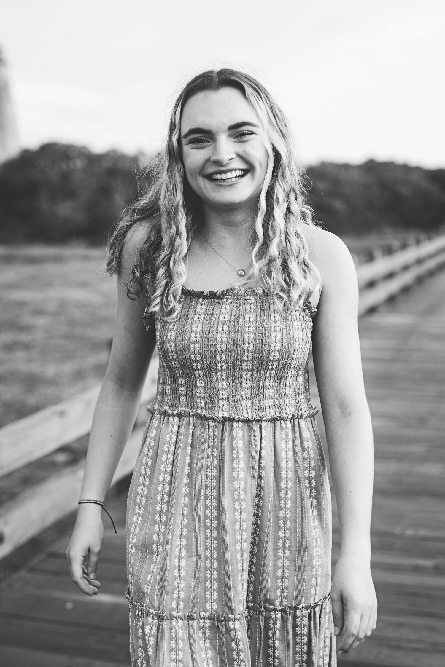 Black and white candid portrait on wooden boardwalk with natural lighting.