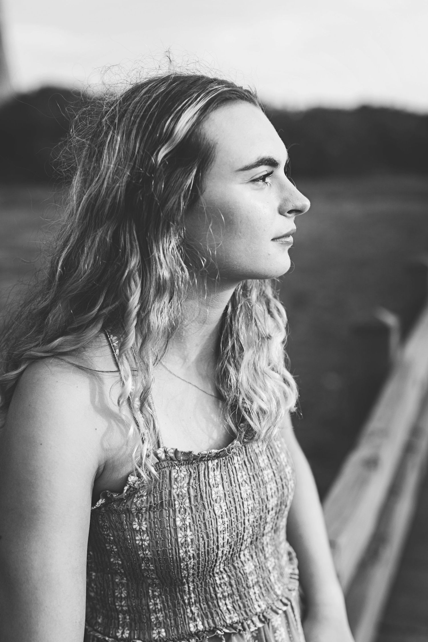Side profile portrait in black and white showing textured dress and wavy hair.