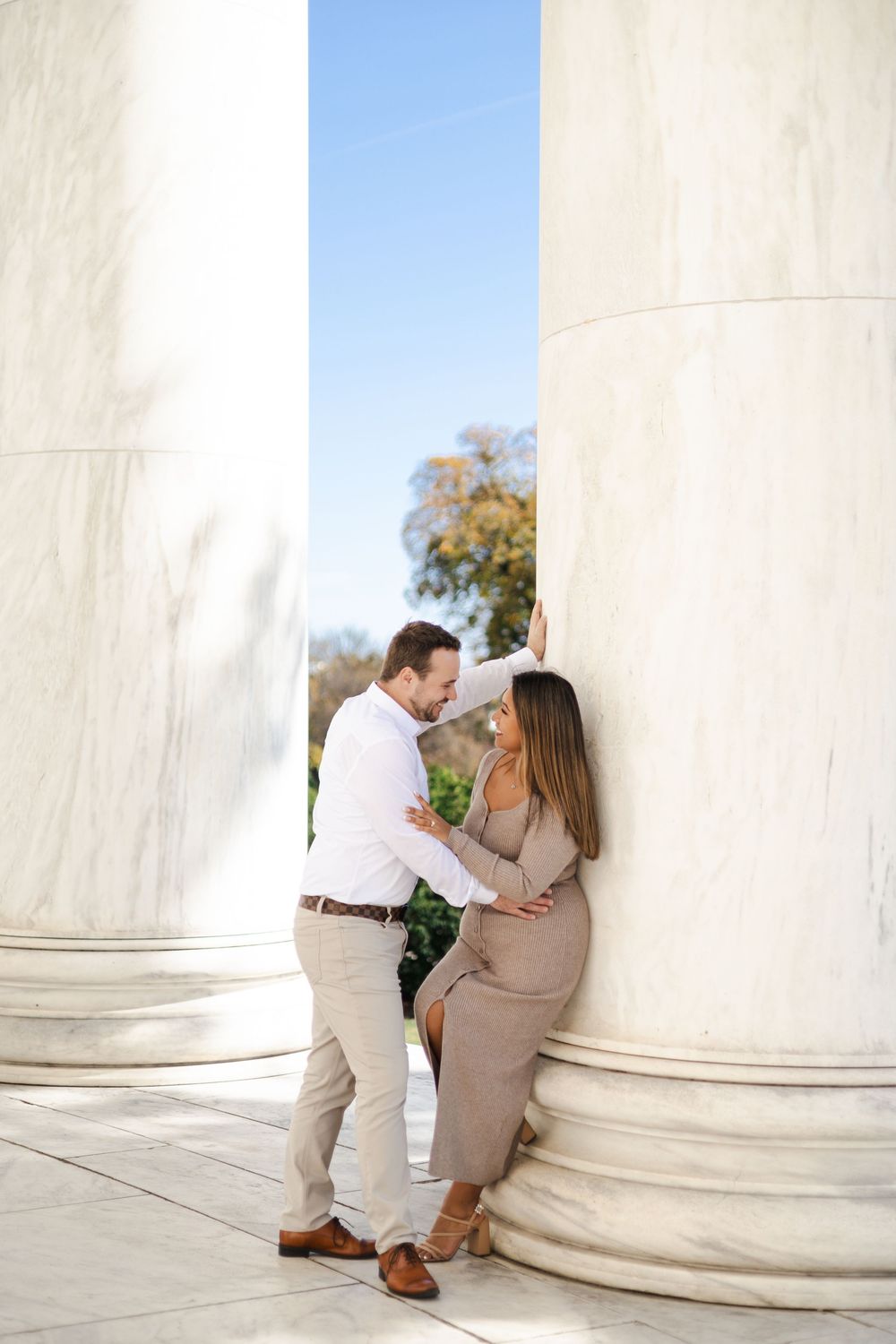Couple sharing a romantic moment between large white marble columns at the Jefferson Memorial in Washington DC.