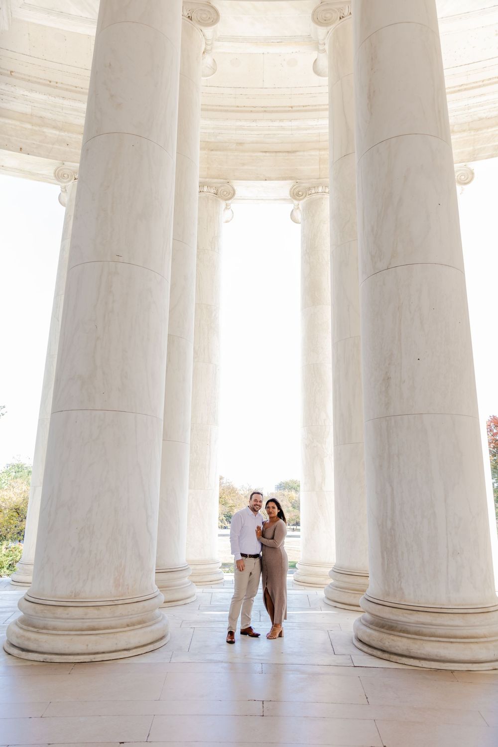 Couple posing between white marble columns at the Jefferson Memorial in Washington, D.C.