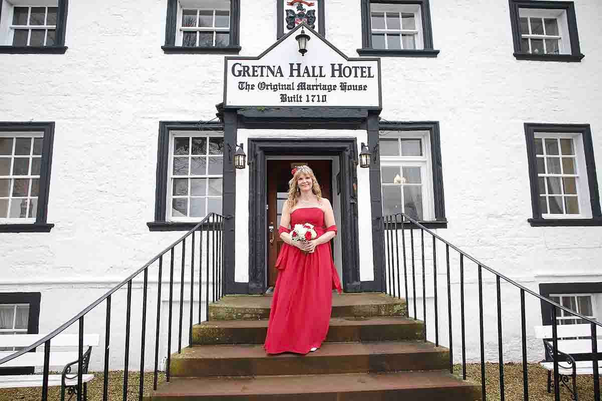 Bride in a red wedding dress outside Gretna Hall, the historic marriage house built in 1710.