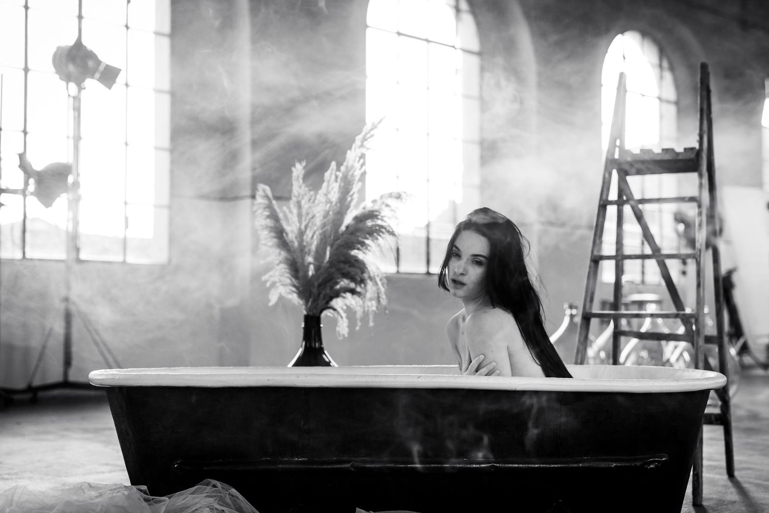 Foto glamour in bianco e nero di una modella all'interno di una vasca da bagno d'epoca immersa nel fumo.