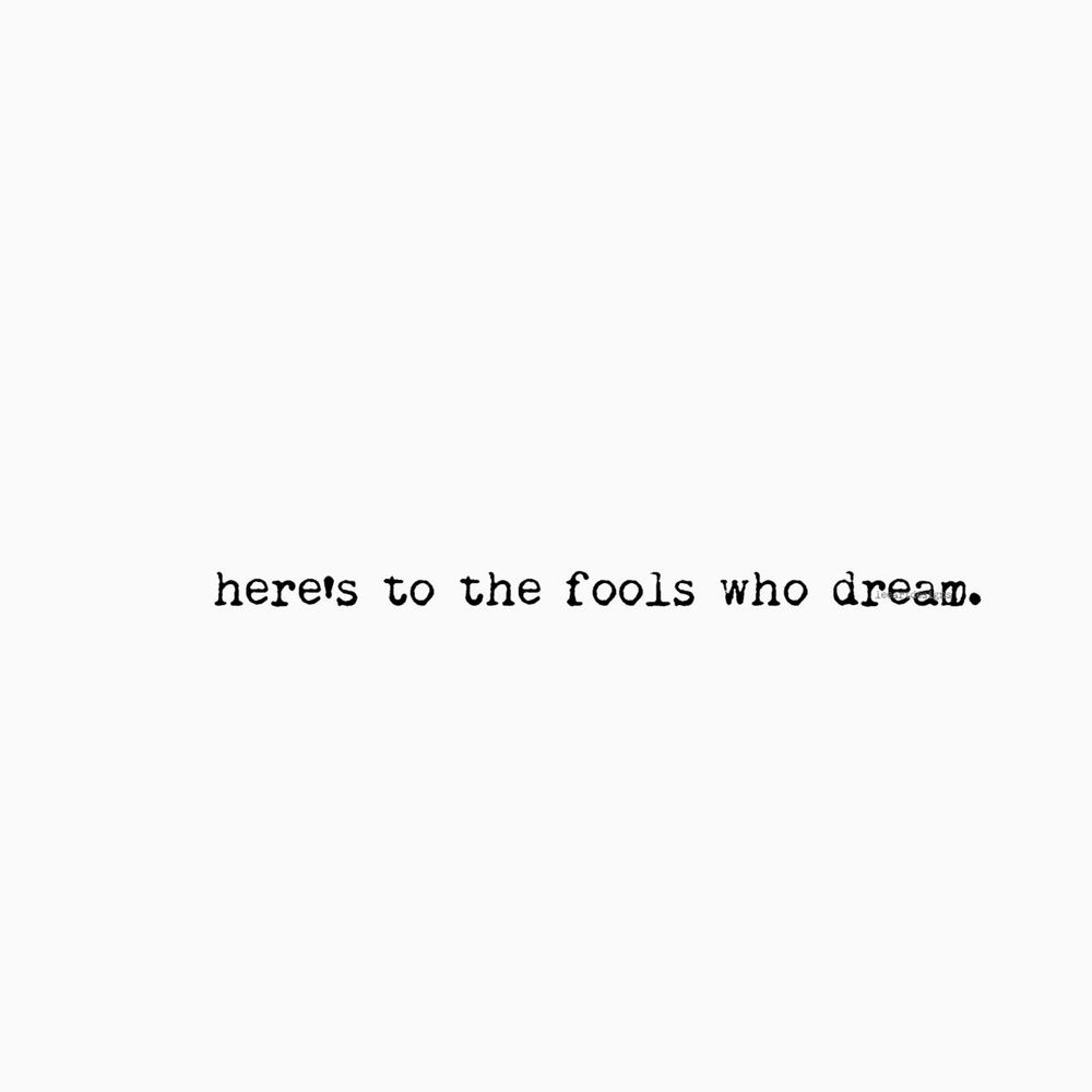 Minimalist white background with typewriter font quote reading here's to the fools who dream.