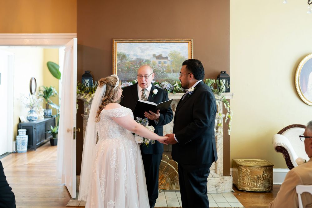 Bride and groom exchange vows with officiant during intimate indoor wedding ceremony in elegant venue.