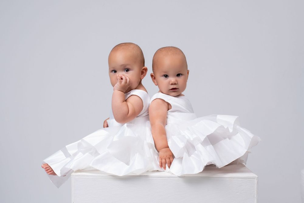 Twin babies wearing white dresses during milestone baby photography