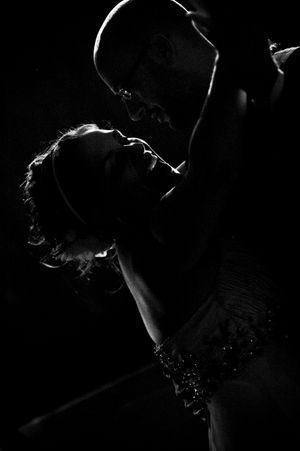 Dramatic black and white silhouette of a couple sharing a romantic dance in dim lighting.