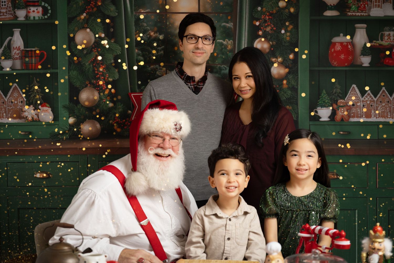 Asian family of four posing playfully in casual outfits against a gray studio background.