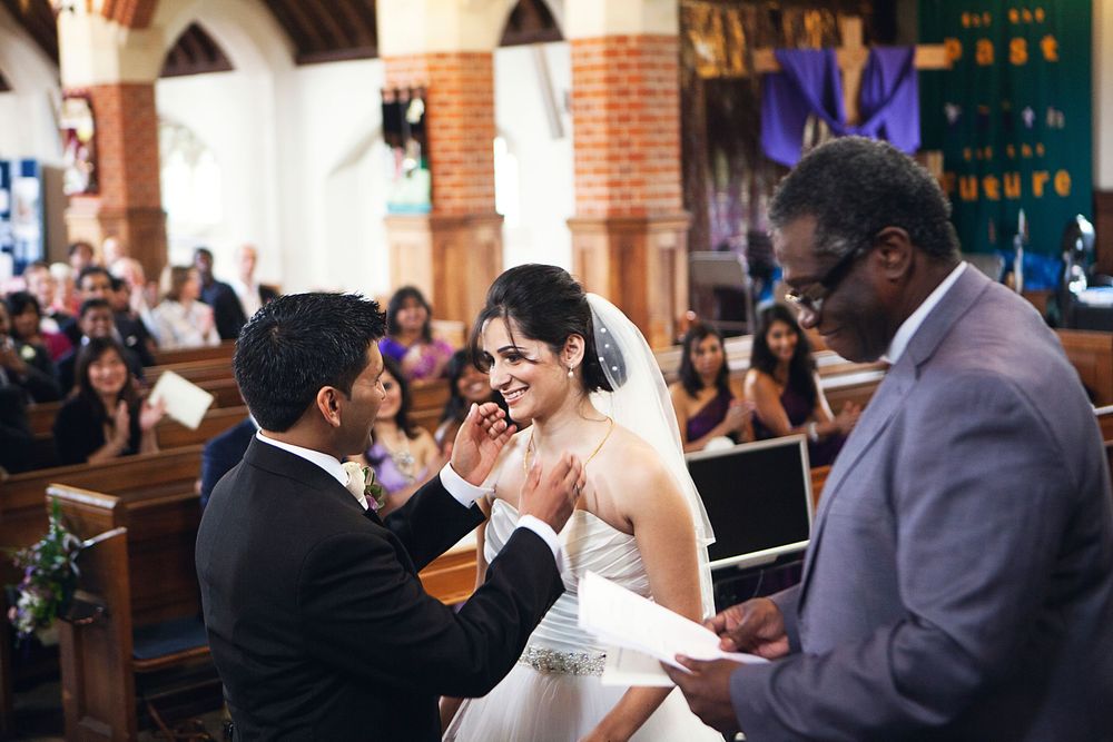 Bride and groom exchange rings at altar during indoor church wedding ceremony.