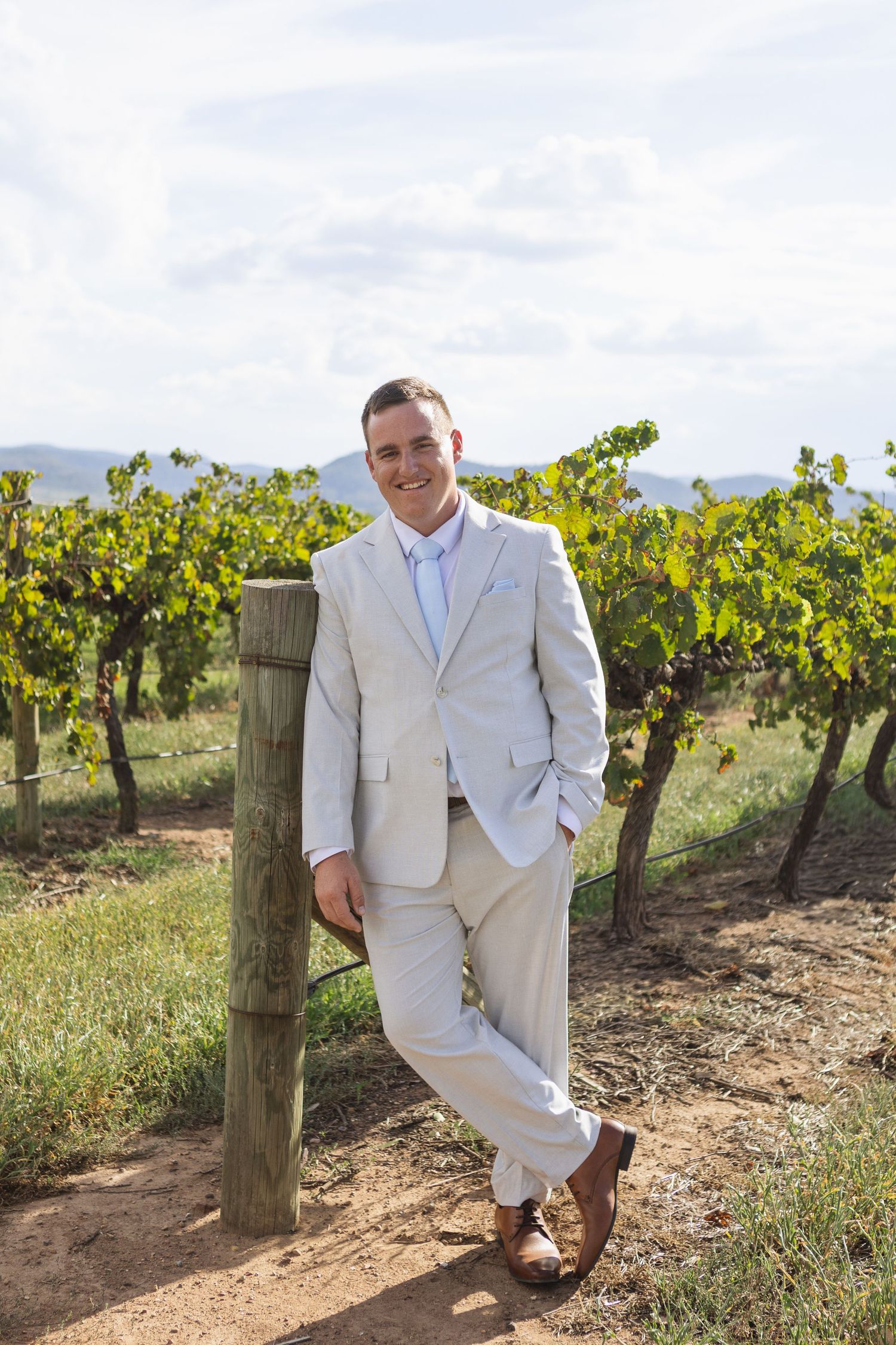 groom leaning against post at Two Rivers Winery Wedding in Denman