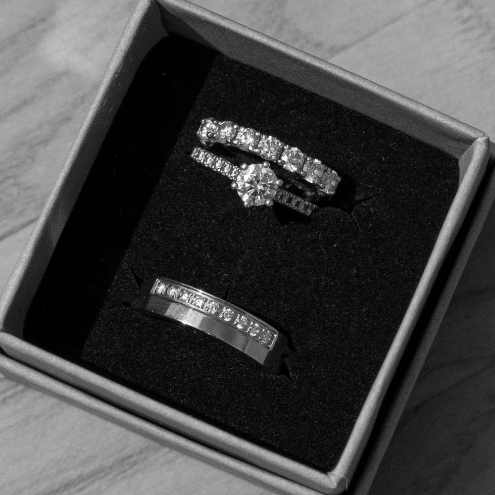 Black and white photo of a wedding ring set in a jewelry box, featuring a diamond engagement ring and a mens band.