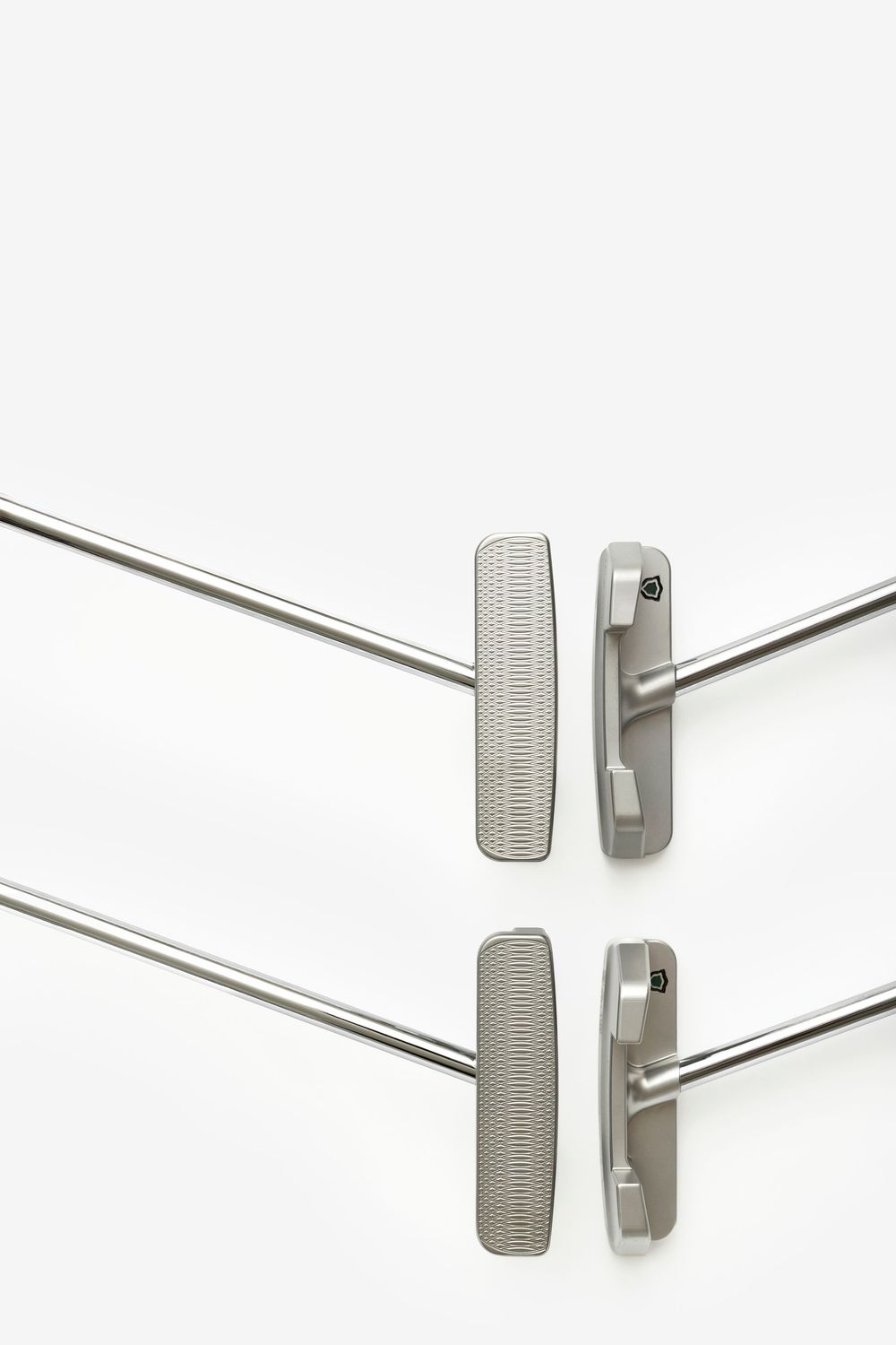 Two stainless steel golf putters with textured grips displayed side by side on a white background.