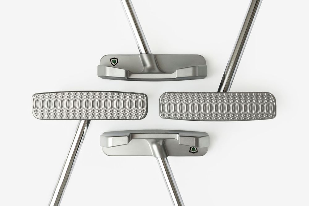 Four silver golf putters arranged symmetrically on a white background, showcasing textured faces and sleek steel shafts.