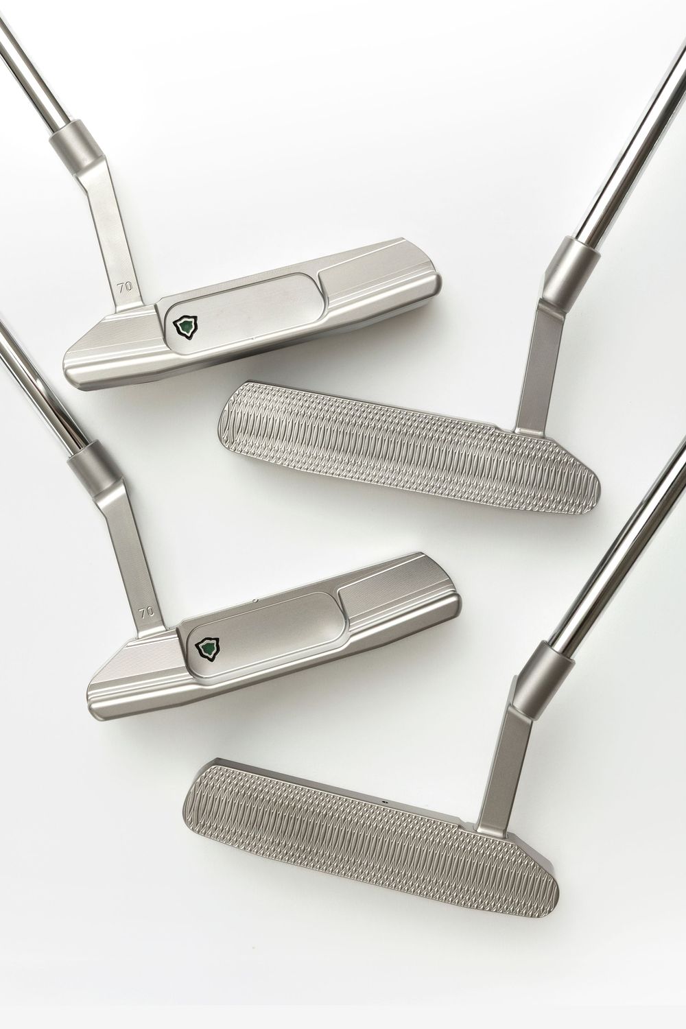 Four silver golf putters arranged on a white background, featuring textured faces and classic blade-style heads.