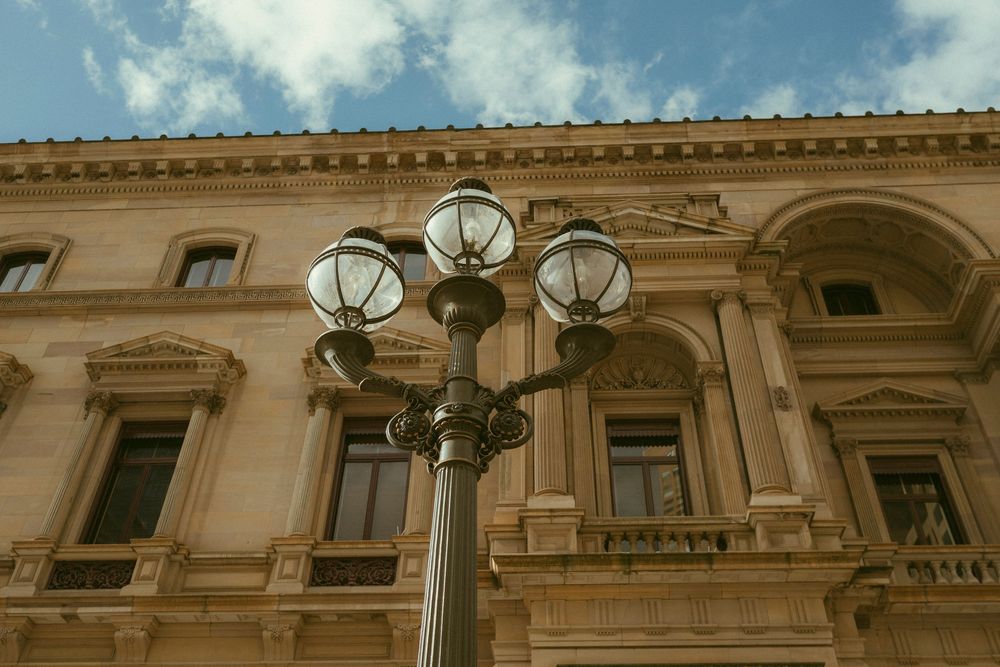 Ornate neoclassical building facade with elegant vintage street lamp against blue sky.