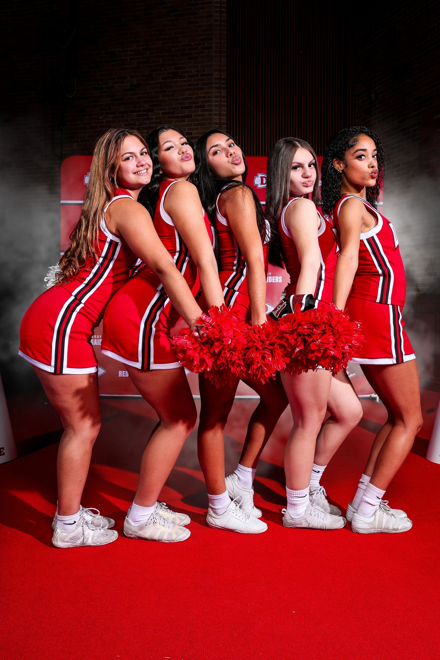 JLHS Cheer squad poses in black and gold uniforms for a team photo at a cheerleading competition.