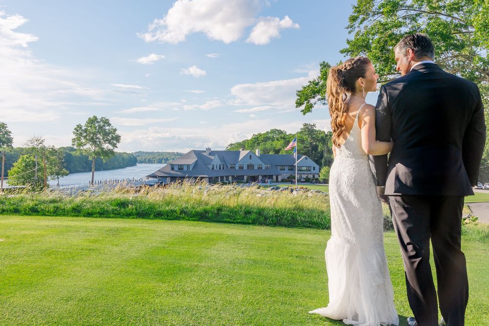 Bride and groom stand together overlooking a scenic waterfront golf course on their wedding day.