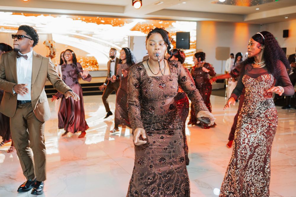 Group of elegantly dressed people dancing at a formal event on a white dance floor.