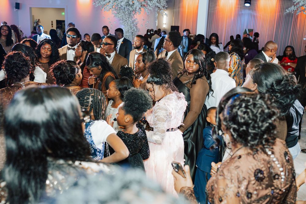 A large crowd of elegantly dressed guests celebrating at a formal event in a decorated banquet hall.