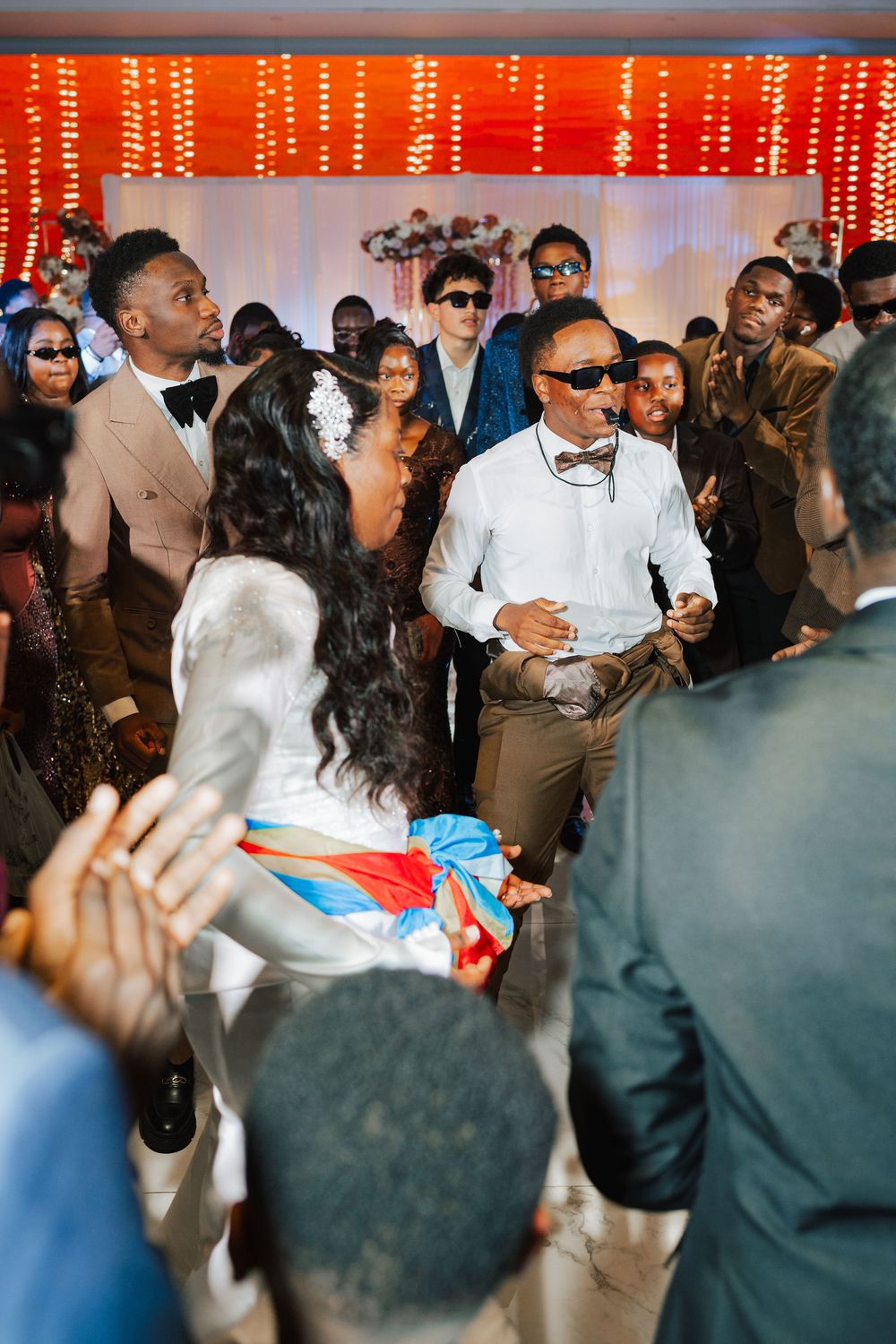 Guests celebrate on the dance floor at a vibrant African wedding reception with colorful decorations.