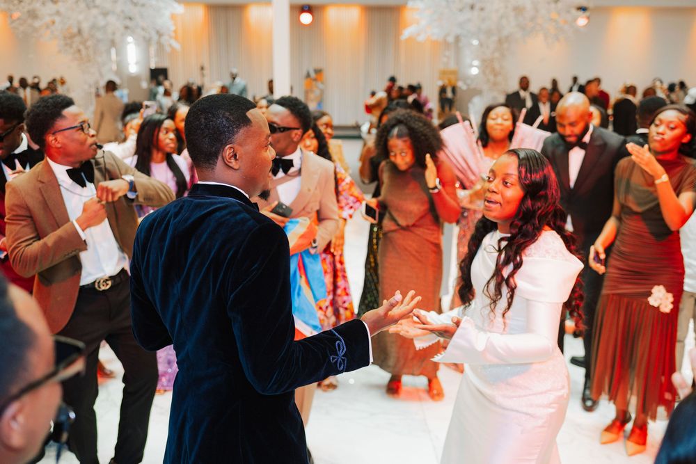 Bride and groom share joyful dance moment with guests at lively wedding reception celebration.