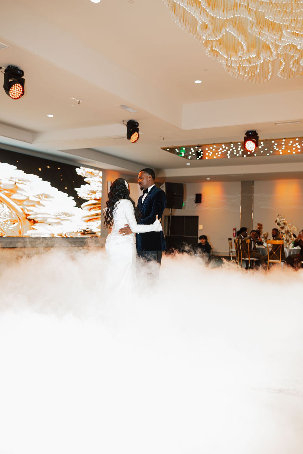 Newlyweds share an intimate first dance moment on a fog-covered dance floor at their wedding.