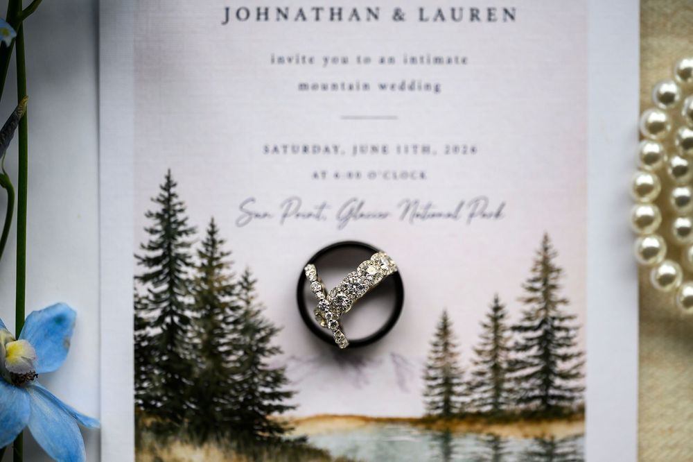 Wedding rings rest on an elegant invitation for Johnathan & Lauren's mountain wedding at Glacier National Park.