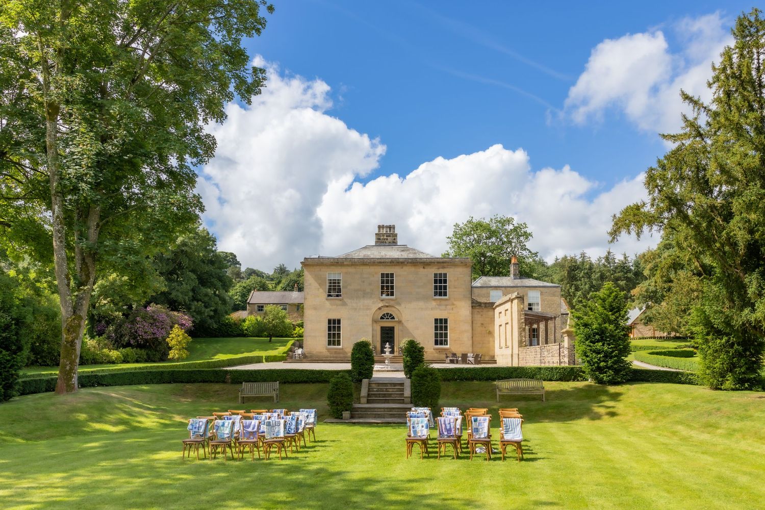 Grassfield Hall, Pateley Bridge - Grand Georgian country house surrounded by lush green lawns with chairs arranged ready for a wedding.