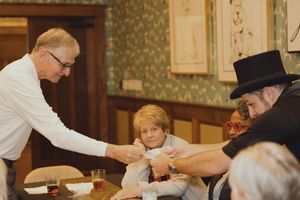 A magician performs a close-up card trick for seated guests at an elegant dining event.
