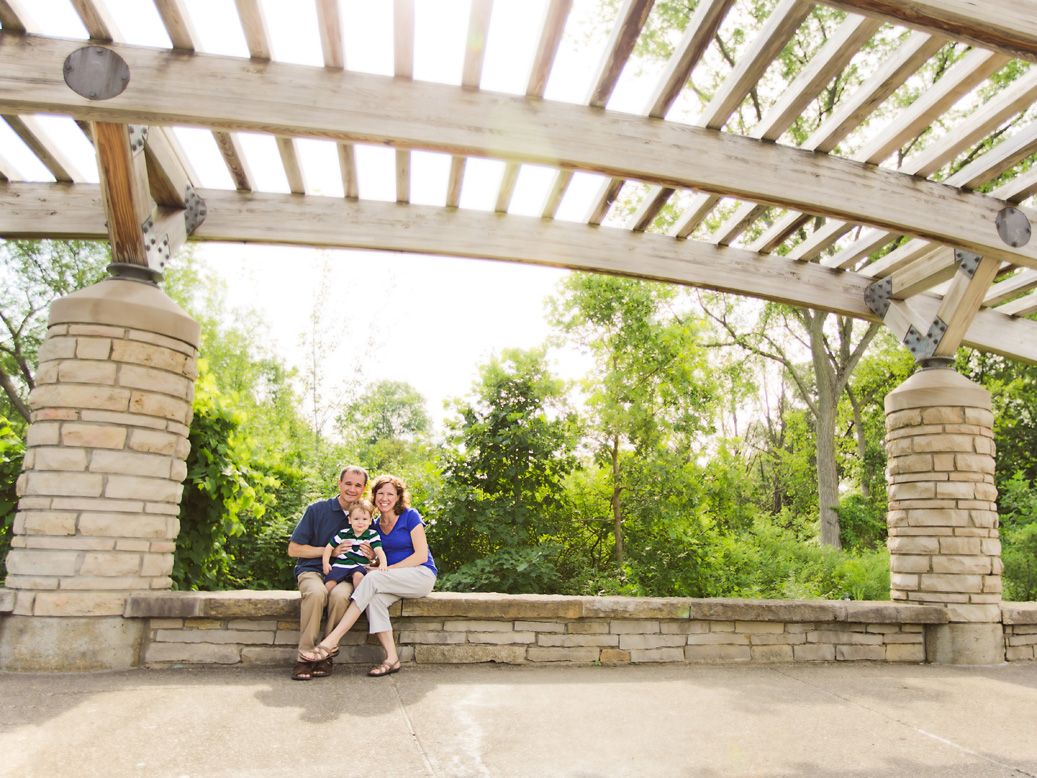 Outdoor family pictures on stone bench under grand wooden pergola at Matthaei Botanical Gardens in Ann Arbor, MI