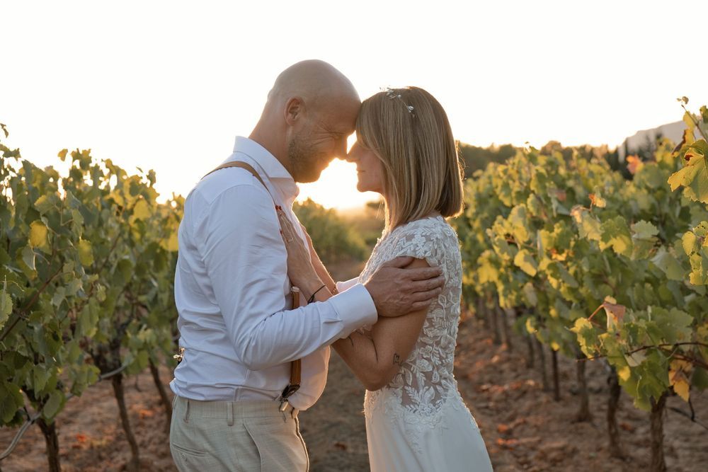 Delphine et Christophe, front contre front dans les vignes de Pourrières au coucher du soleil, le jour de leur mariage.