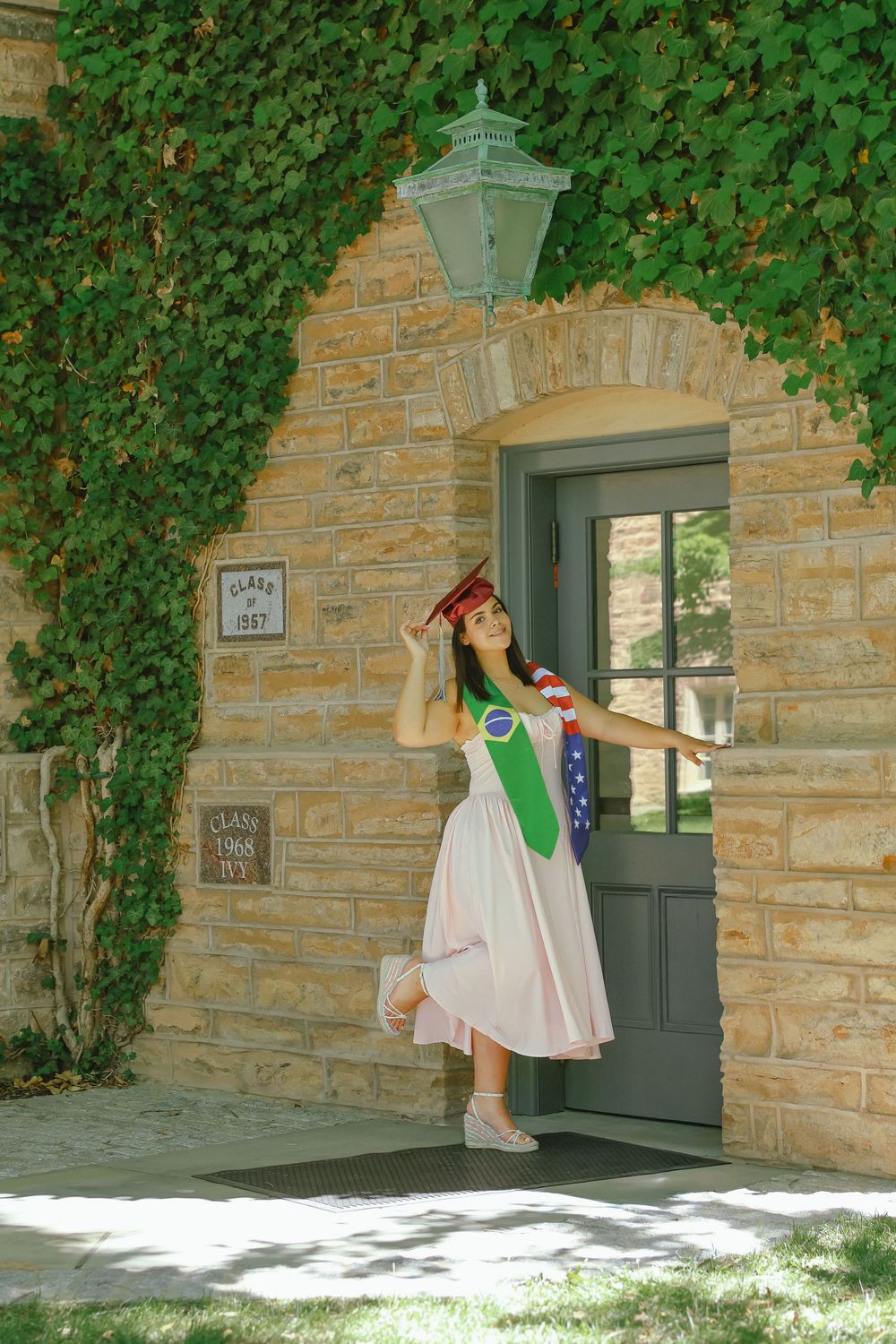 Graduate in a white dress and stole posing by an ivy-covered stone doorway, NJ graduation photos