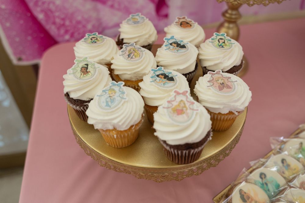 Gold tray of frosted cupcakes on a pink dessert table at a first birthday party in New Jersey