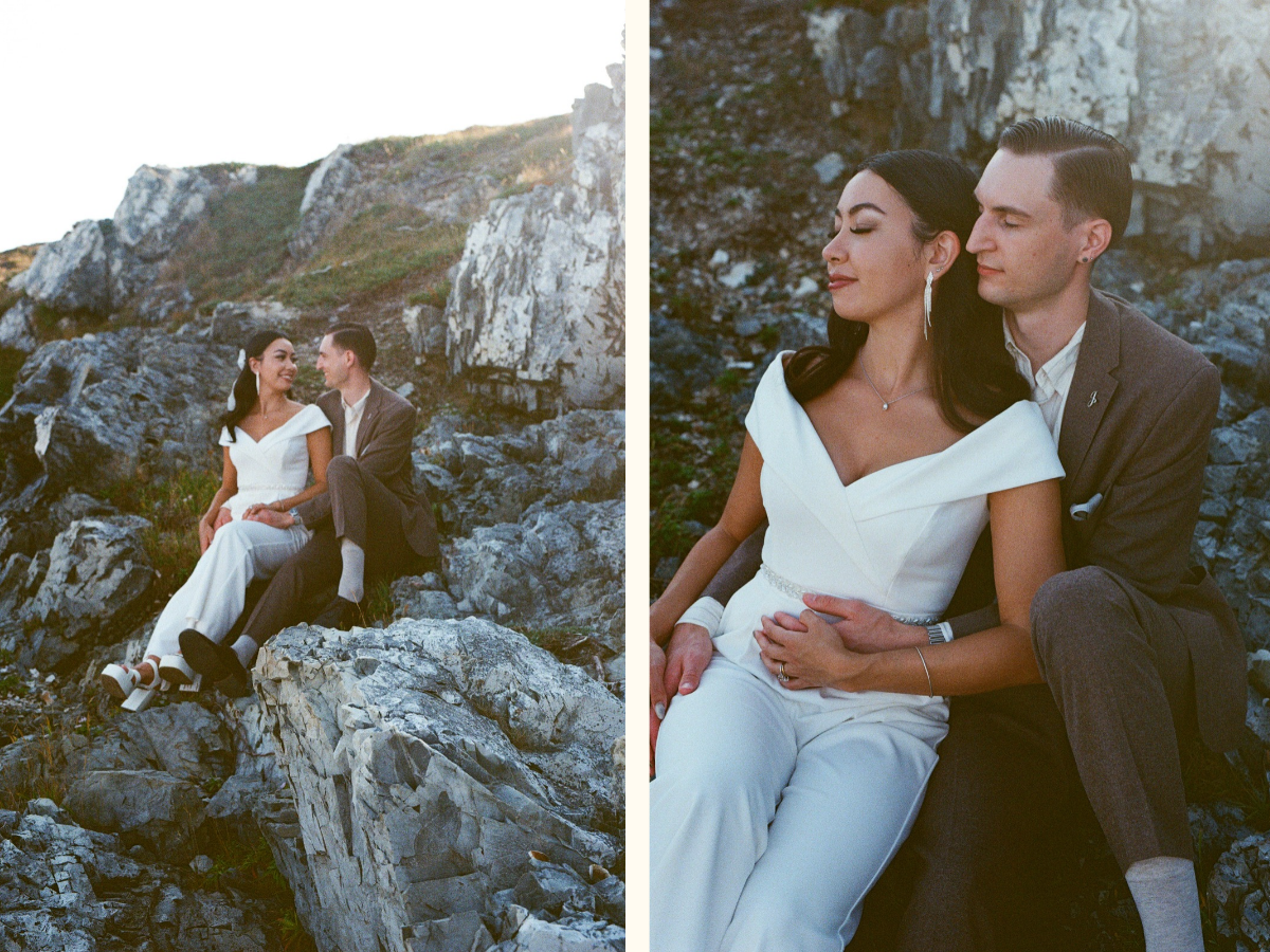 35 mm film photo of bride and groom hold each other while sitting on a rocky shore on vancouver island