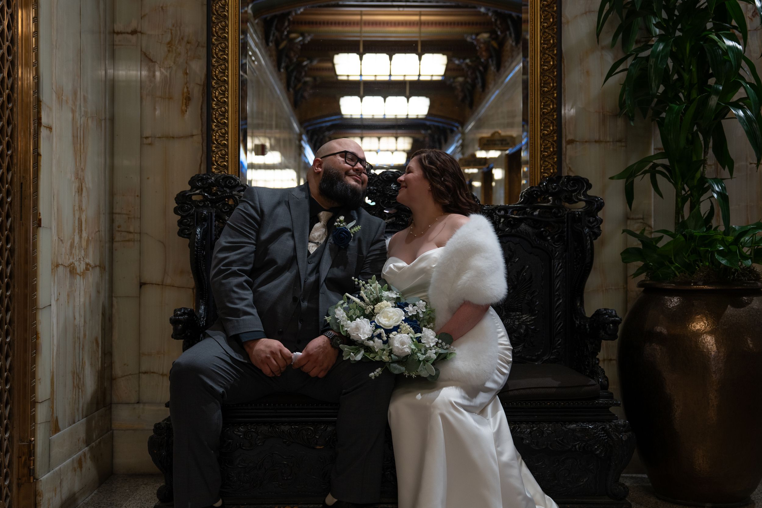Bride and groom share a romantic moment seated on ornate chairs at Smith Tower during their elopement. Captured by Savvy Photography