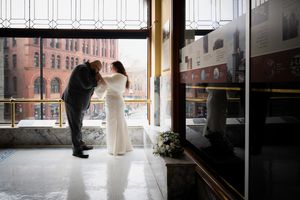 Bride and groom share a tender moment by a large window in Smith Tower during their wedding day. Captured by Savvy Photography