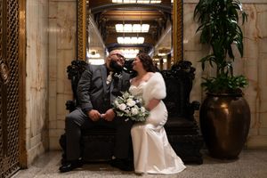 Bride and groom share a romantic moment seated on ornate chairs at Smith Tower during their elopement. Captured by Savvy Photography