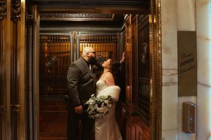 Bride and groom sharing a romantic kiss in an ornate golden elevator in Smith Tower during their wedding day. Captured by Savvy Photography