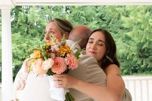 A father hugging both daughters during a backyard wedding Captured by Savvy Photography