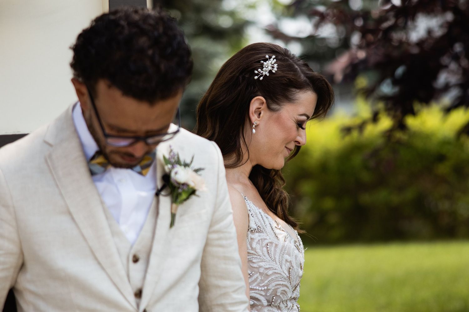 Bride and groom back to back with heads bowed in prayer before their wedding ceremony