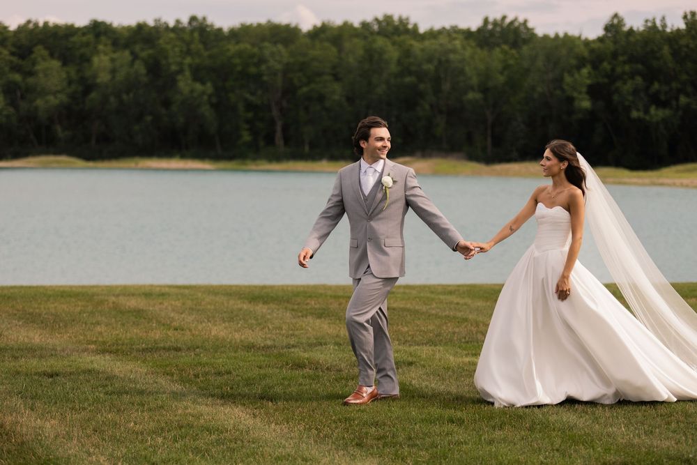 Bride and groom running hand in hand along Lake Oliver at their Tall Oaks Resort wedding in Sheffield Village, Ohio