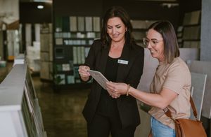 A sales associate helps a customer review a brochure in a modern showroom store.